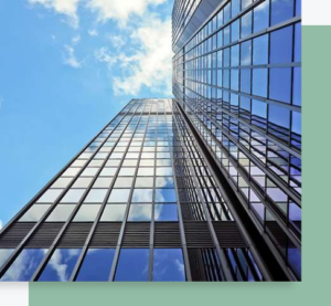 Vue en contre-plongée d’un immeuble tertiaire moderne avec façades vitrées reflétant le ciel bleu