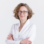 Personne portant une chemise blanche avec les bras croisés sur fond clair