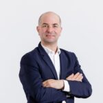 Personne portant une veste bleu marine et une chemise blanche sur fond clair