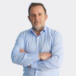 Personne portant une chemise bleue avec les bras croisés sur fond clair