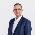 Personne portant une veste bleu marine et une chemise blanche sur fond clair