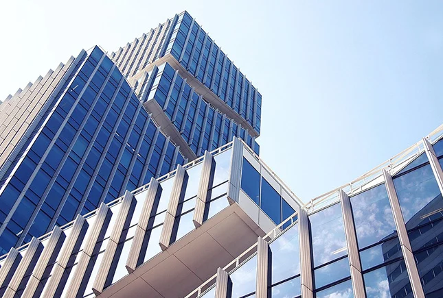 Vue en contre-plongée d’un immeuble tertiaire moderne avec façades vitrées et lignes architecturales géométriques